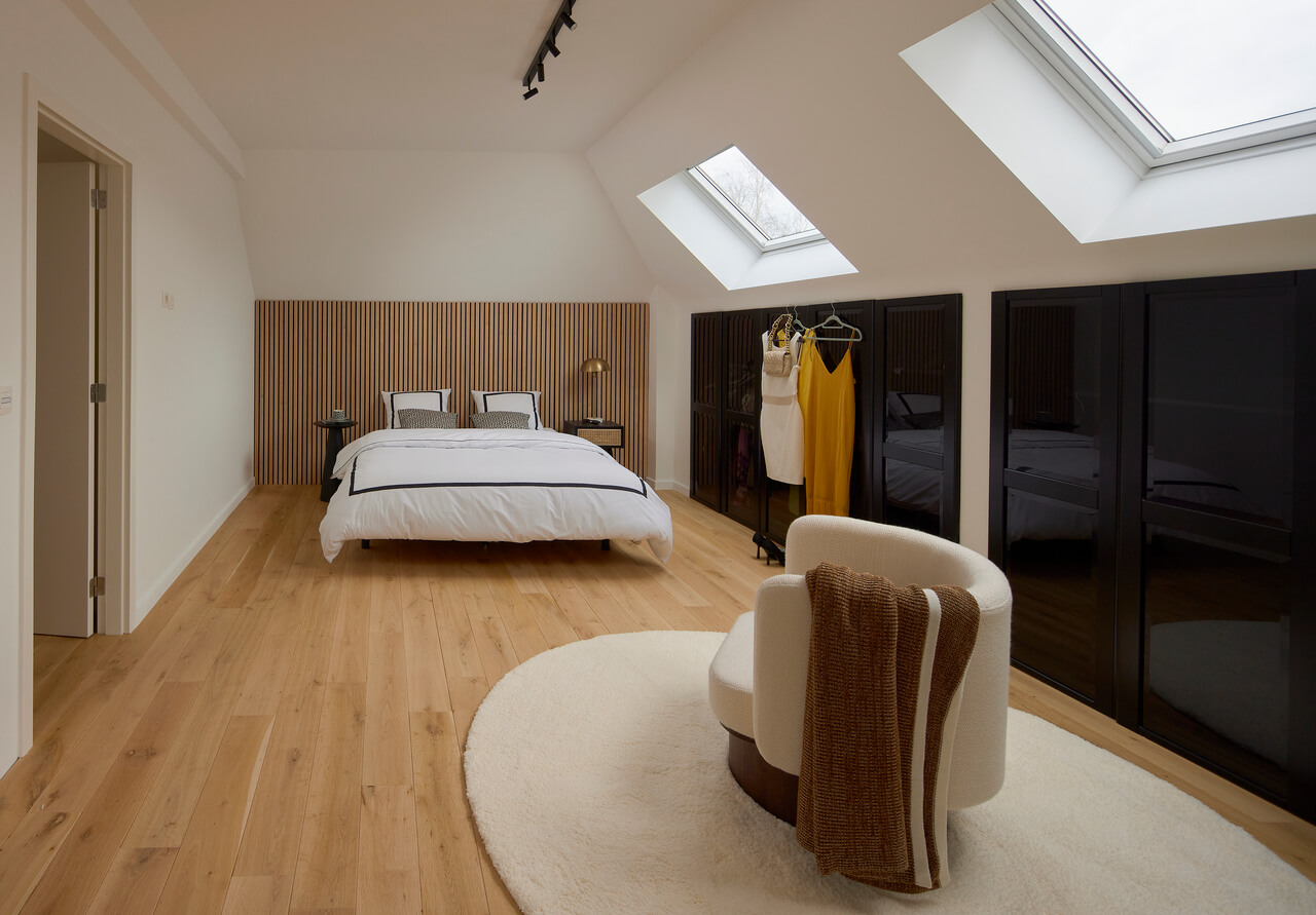 A bright bedroom in the attic with roof windows.