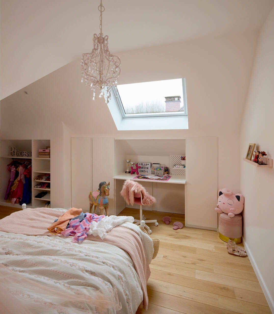 A pastel coloured kids room in the attic with a roof window.