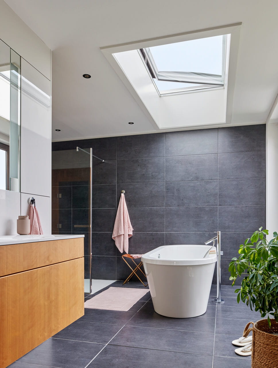 Bathroom with a opened flat roof window above the bathtub.