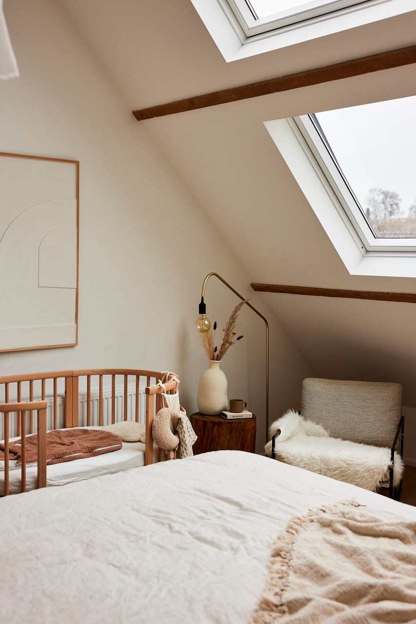 A corner in the bedroom with a baby bed and roof windows.