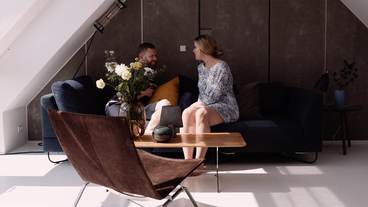 Two people sitting on a sofa and talking.