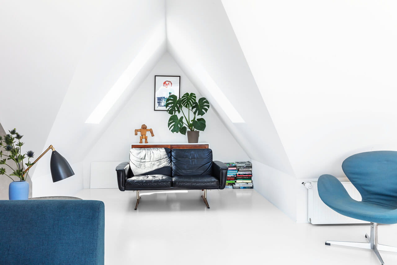Living room space in the white painted attic with roof windows.