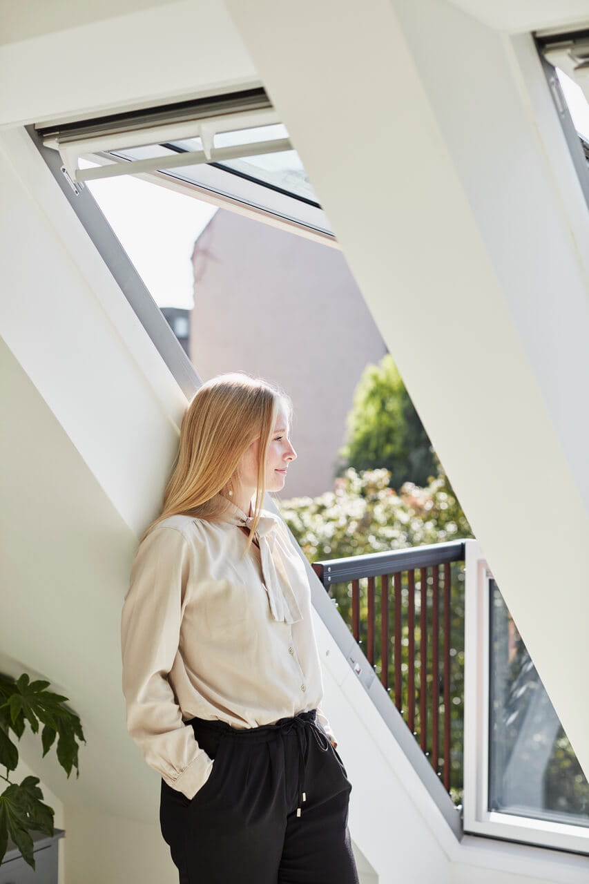 Woman standing by the roof balcony and looking outside.