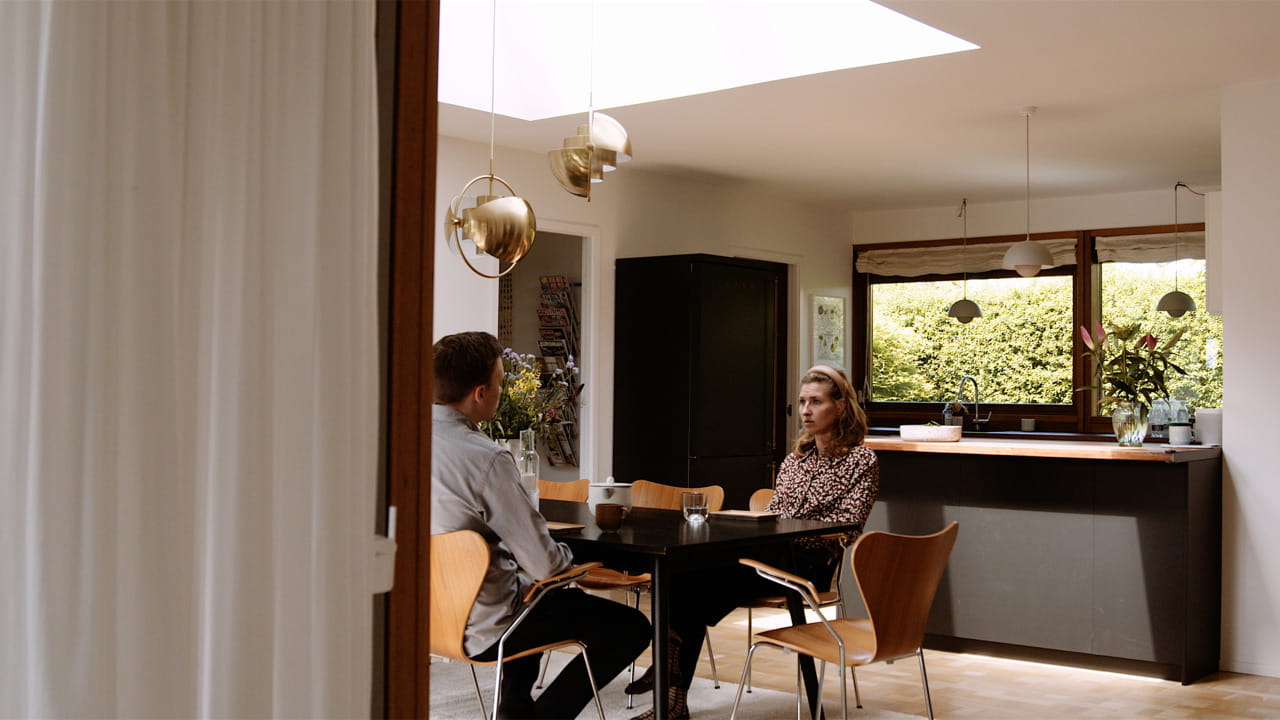Two people sitting by the dining table in the kitchen.