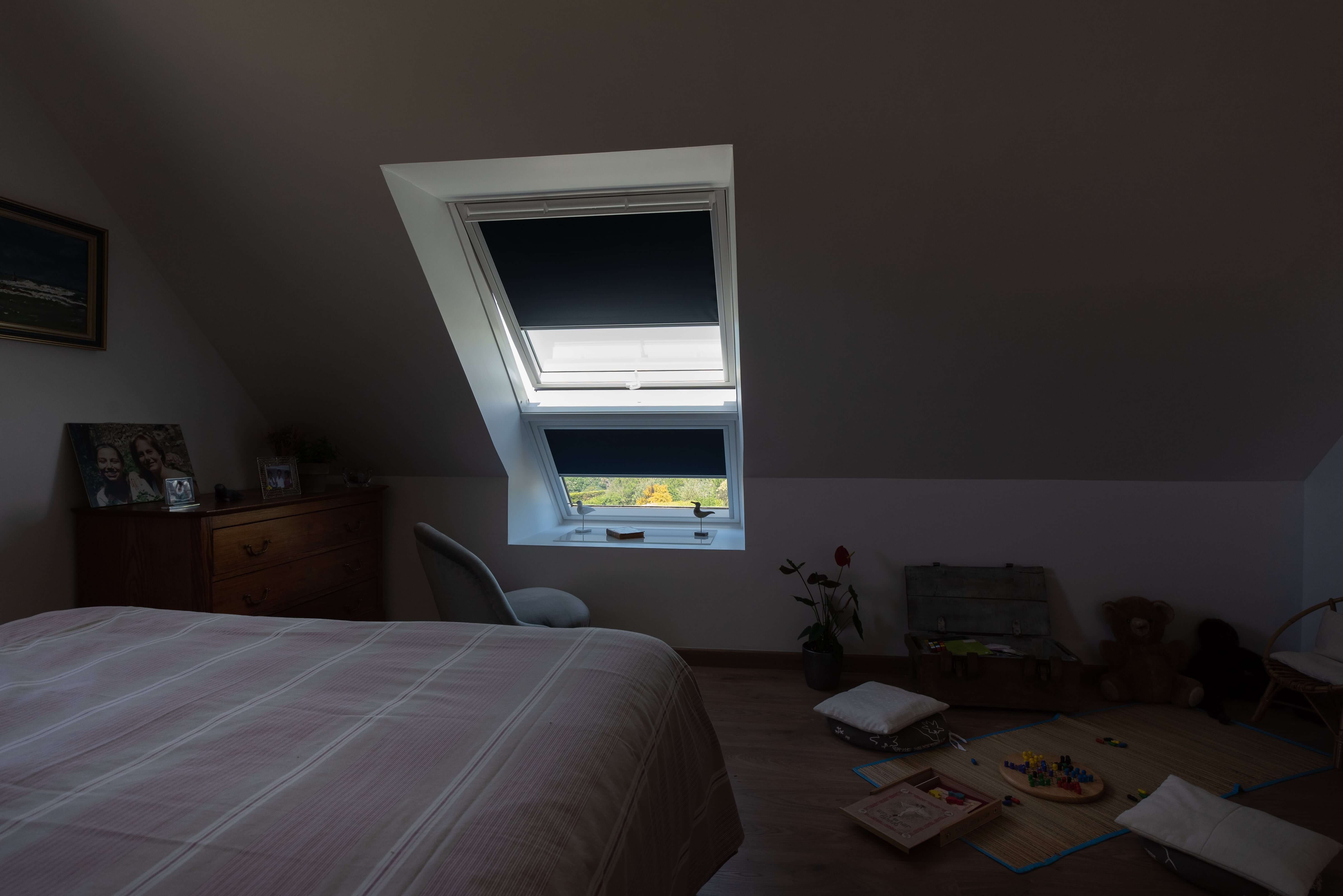 A bedroom with a roof window and blinds