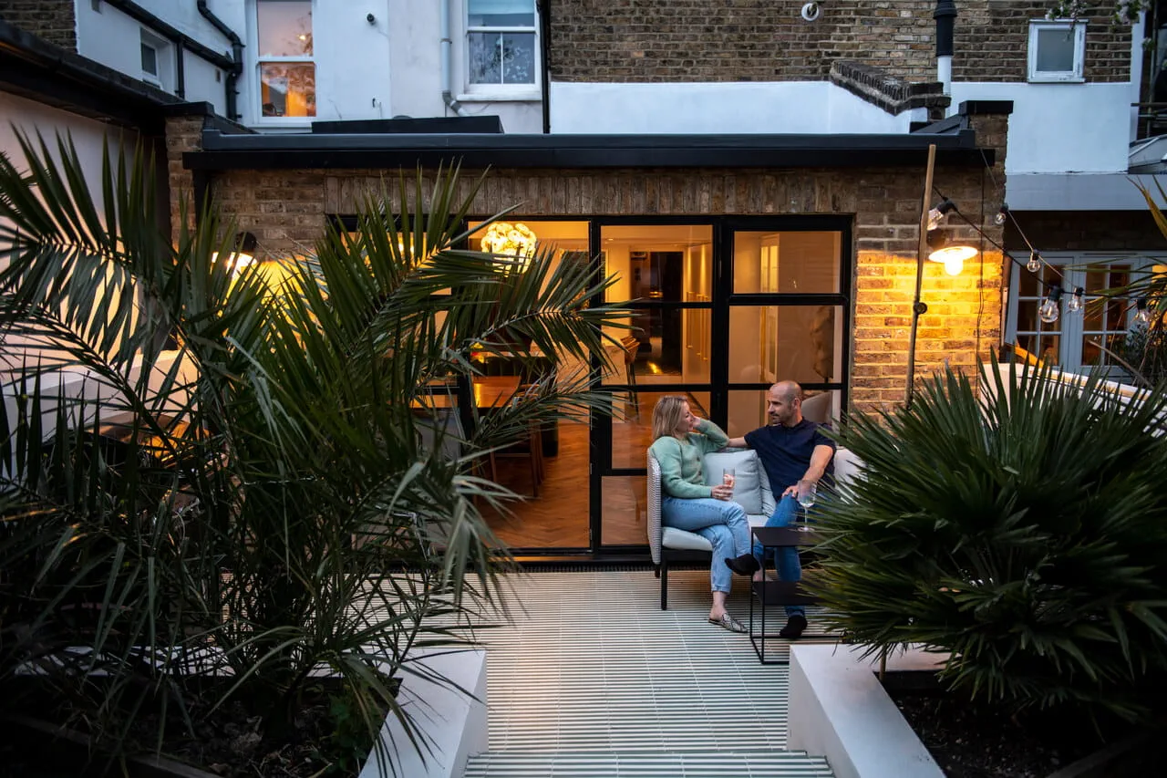 The outside view of the kitchen extension with two people sitting outside in the terrace.
