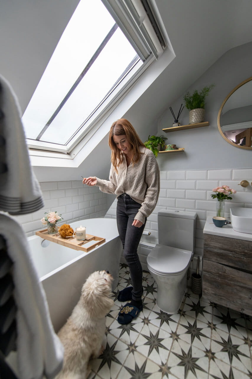 Woman standing in bathroom with a dog.