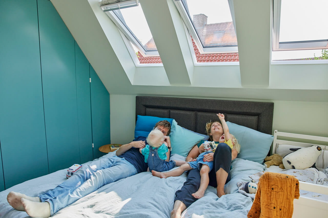 Family lying on the bed and looking up through the roof windows