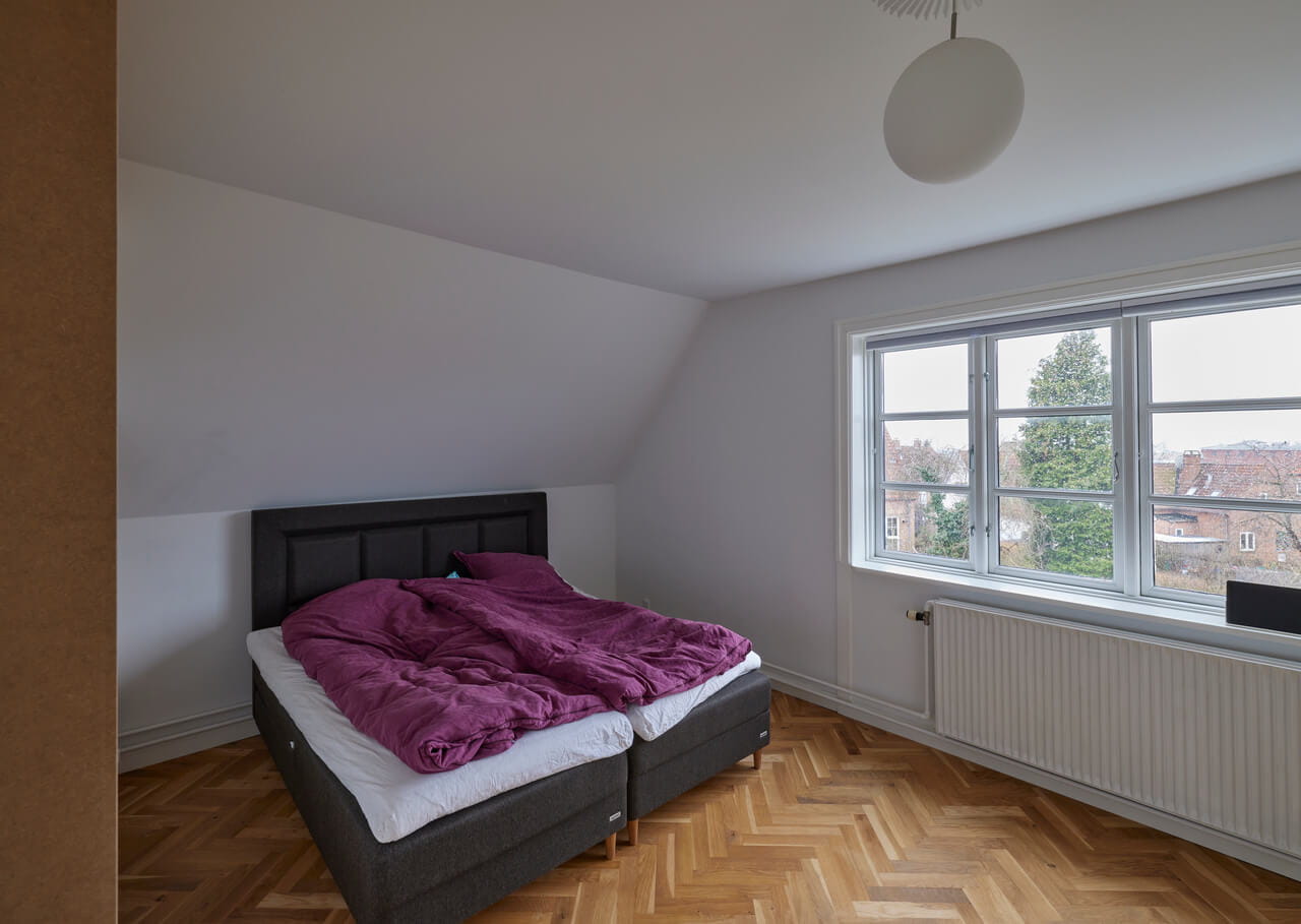 A bedroom with a big window and a bed