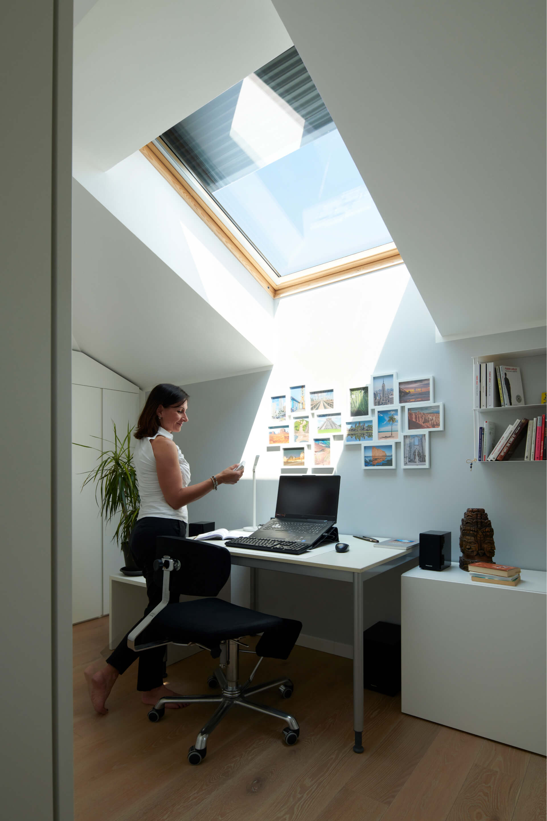 Woman standing in the home office with a big roof window above table