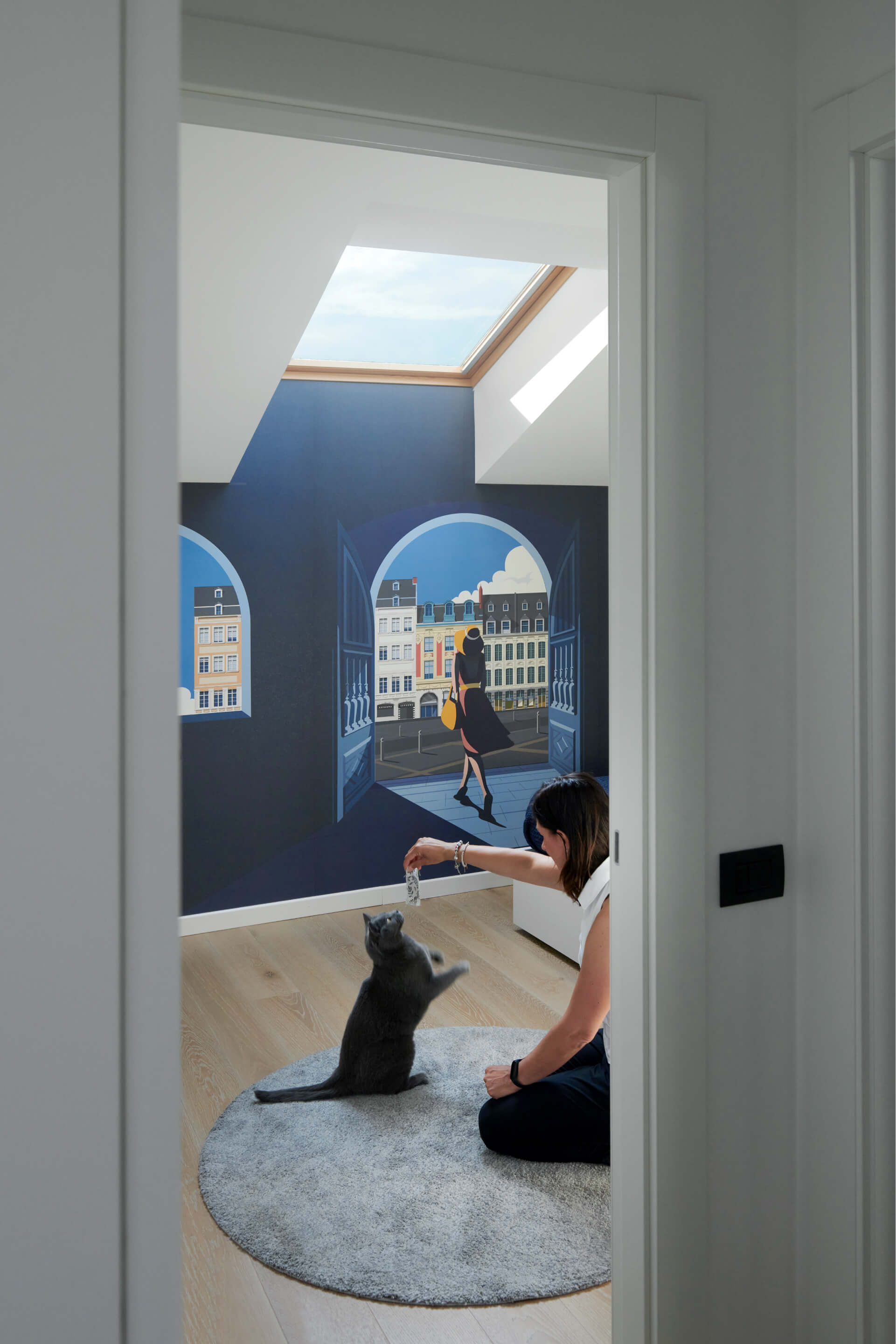 Woman playing with the cat in the blue colored bedroom