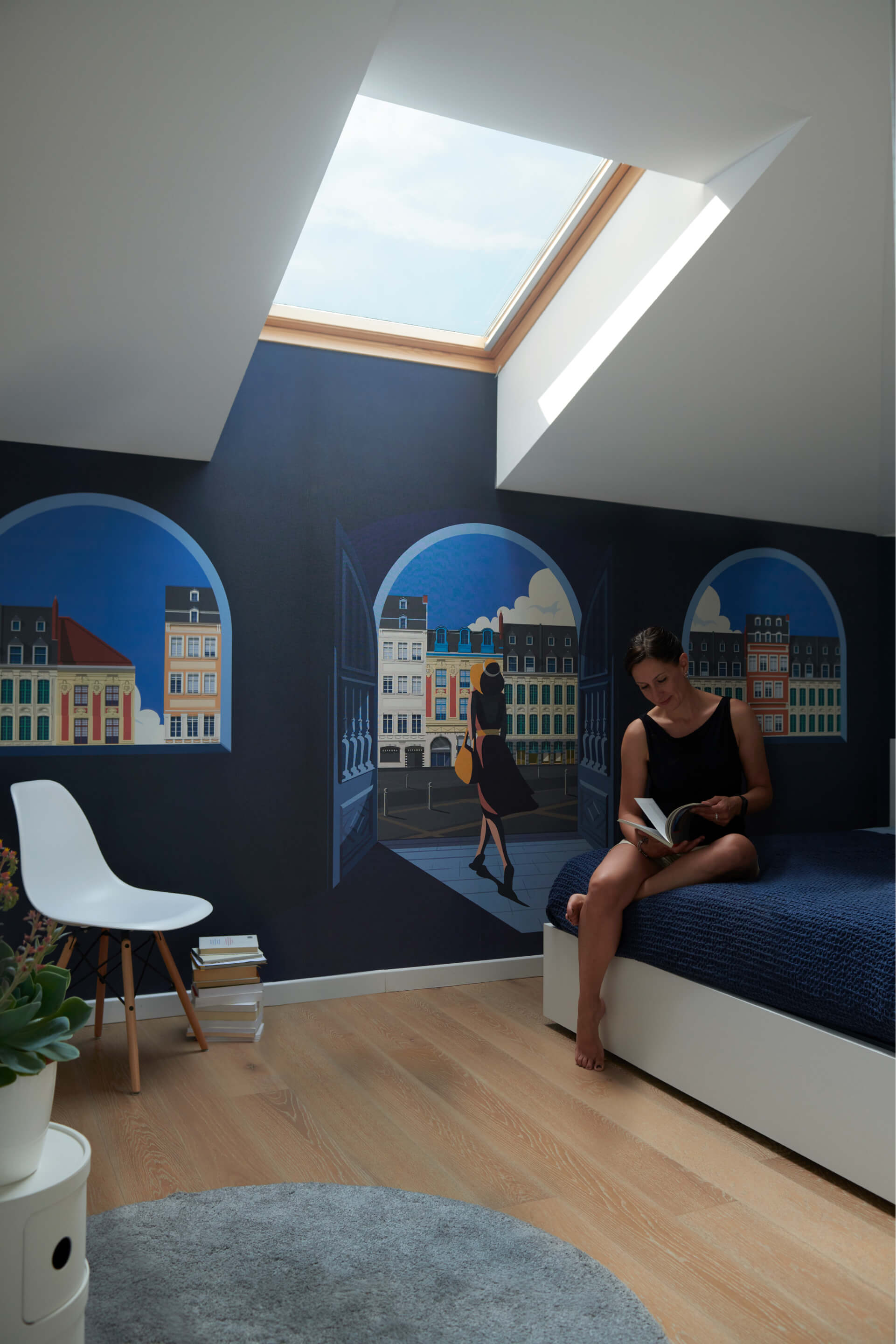 A woman sitting on a bed in the blue painted bedroom