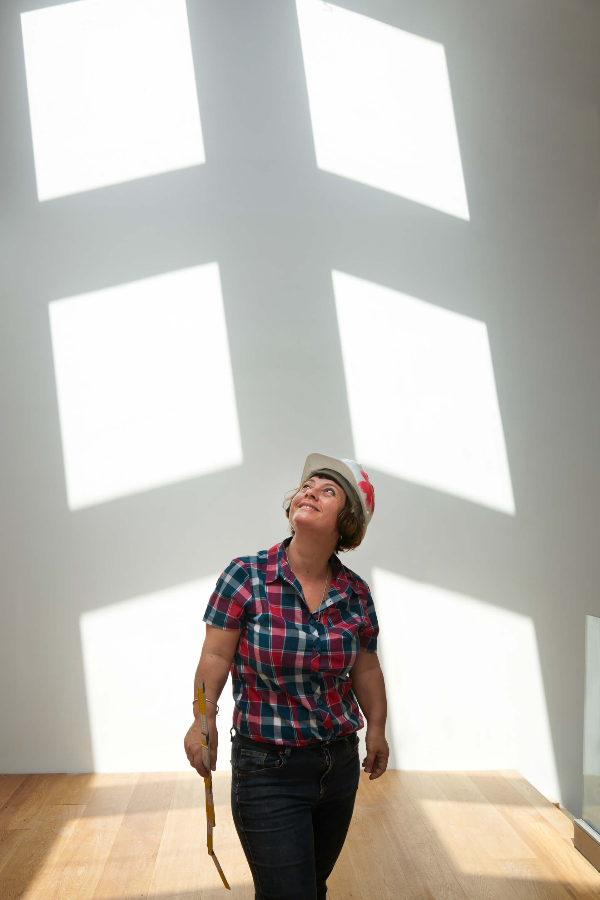 Woman standing in a room with lights coming from a roof window in the background