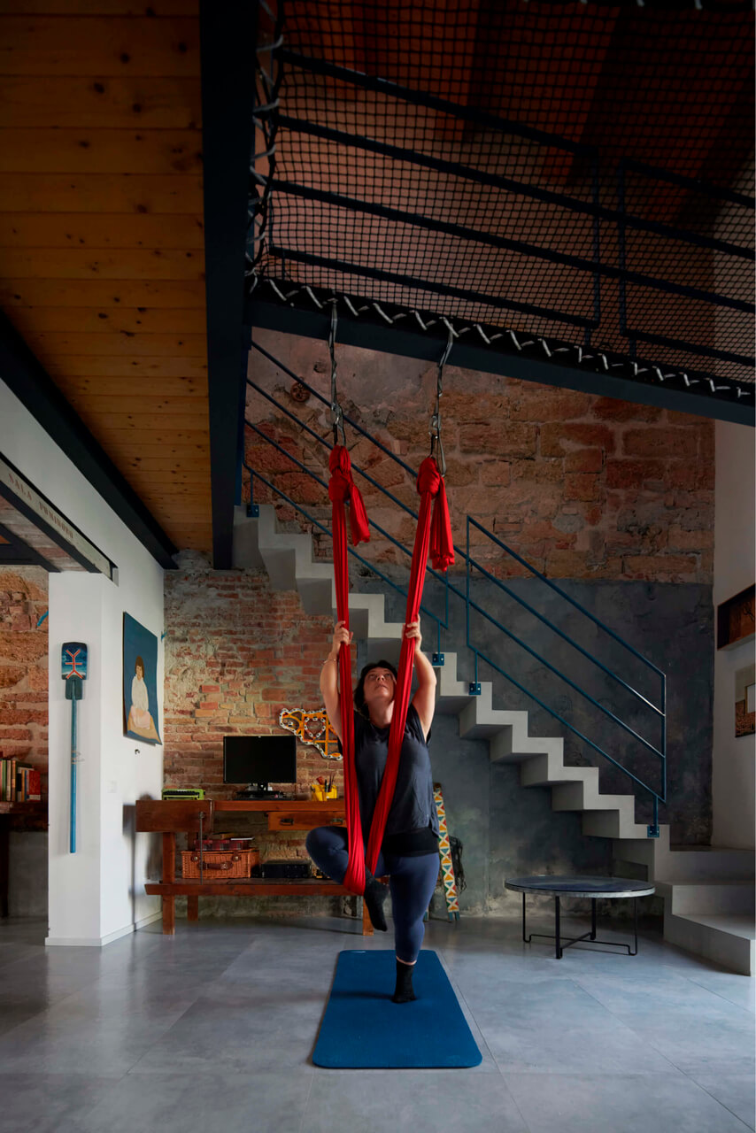 A person using red strips hanging from he ceiling in the open area with staircase