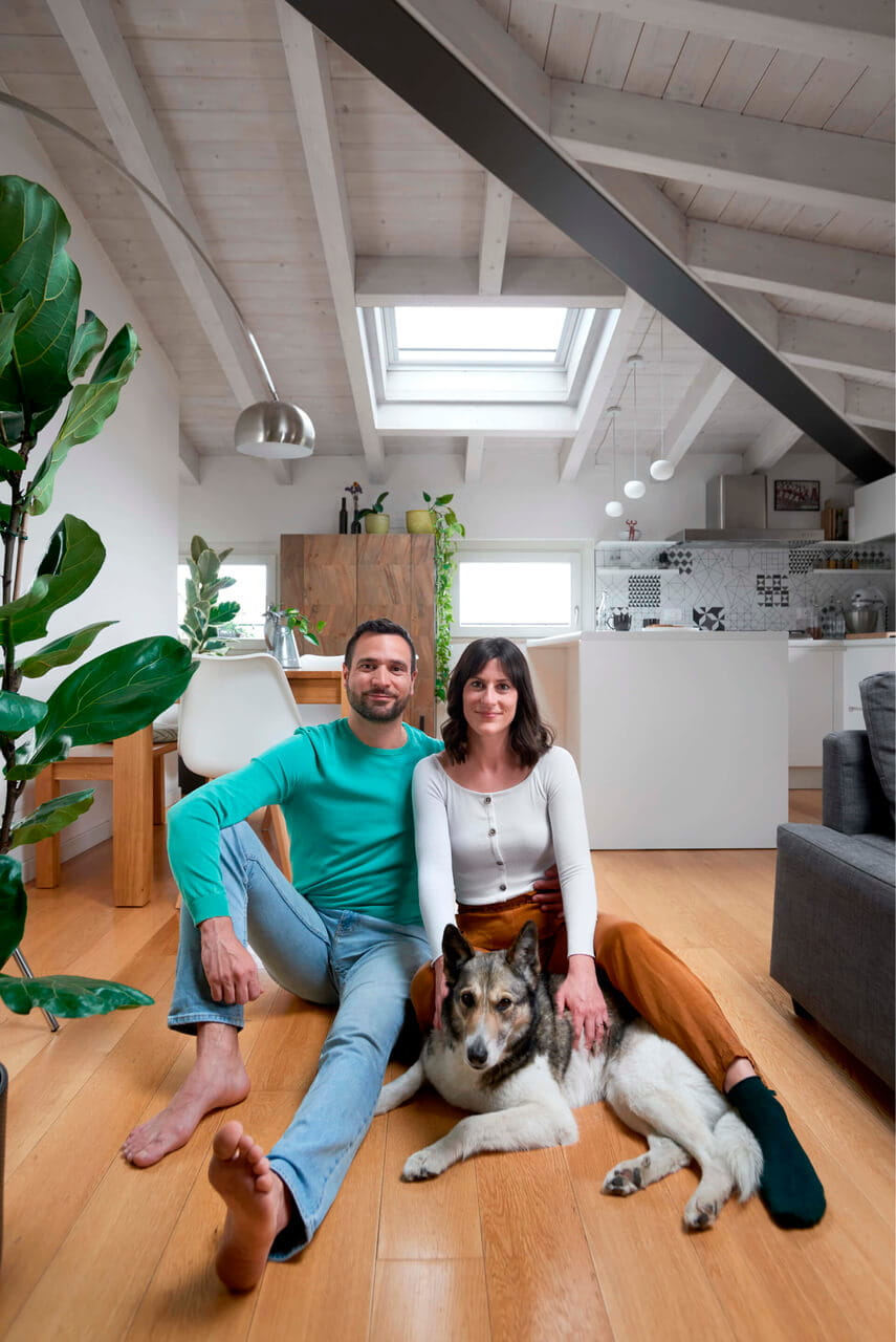 Two persons and a dog sitting on the ground in the attic