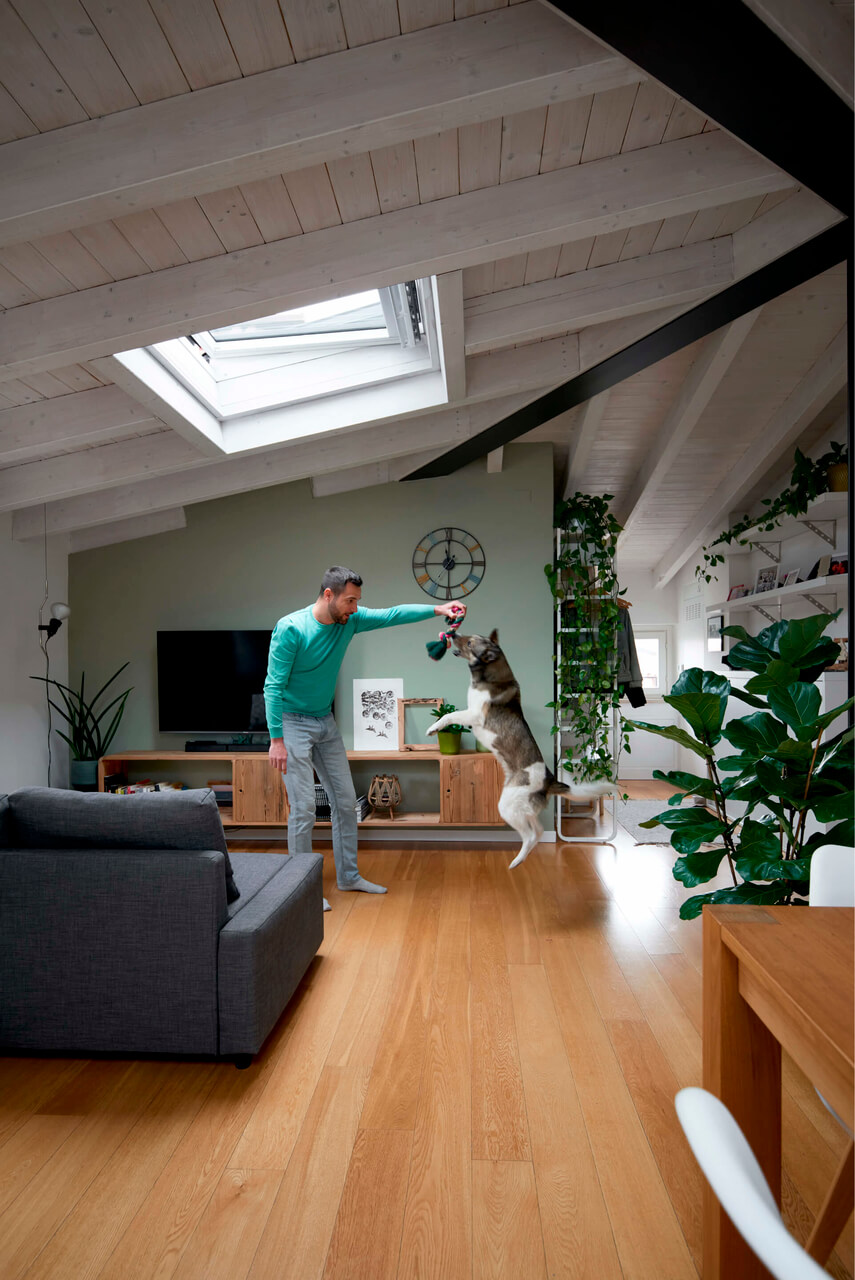 Man standing in the living room area in the attic with a roof window