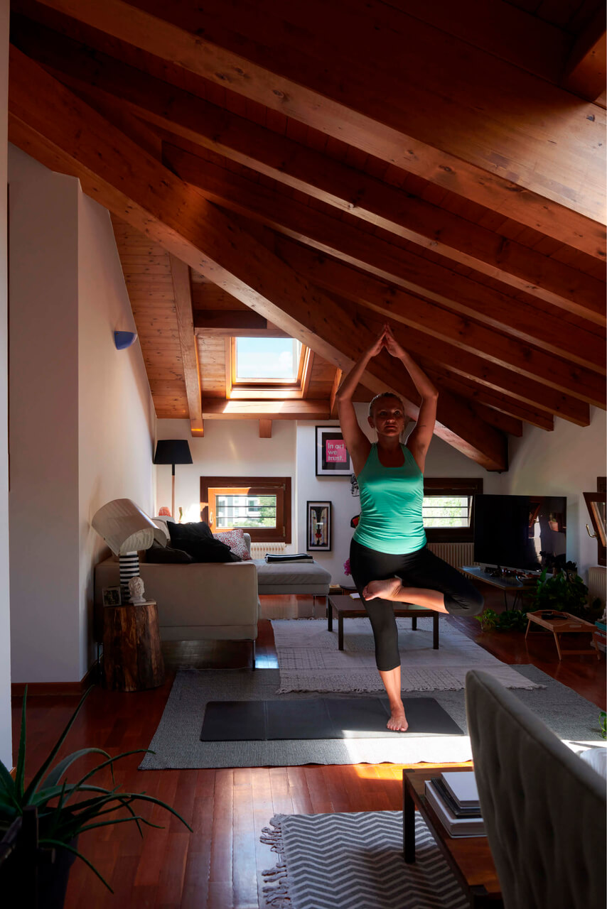 Woman in a green blouse doing yoga in the attic