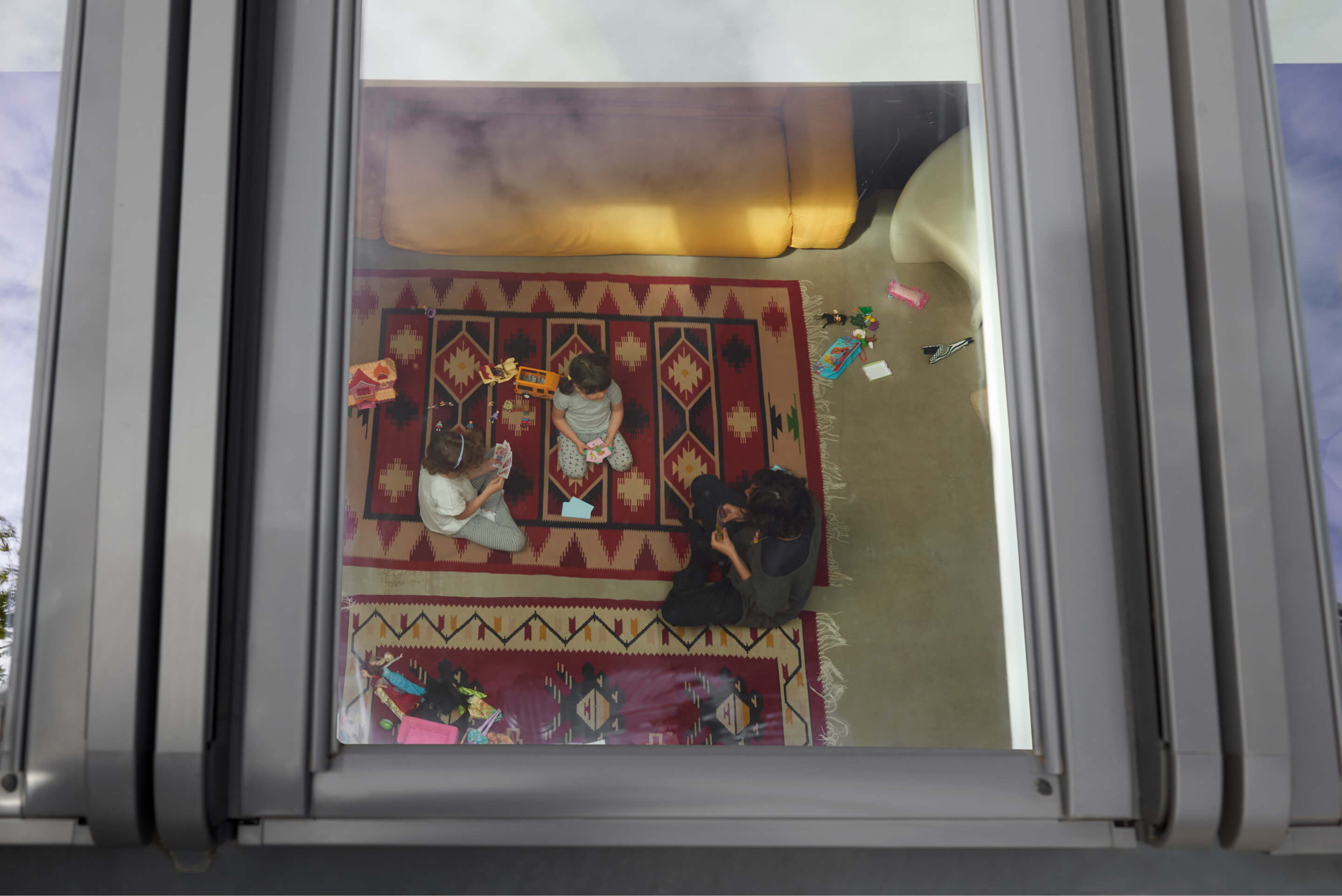 A room through a roof window with a family sitting and playing on a carpet