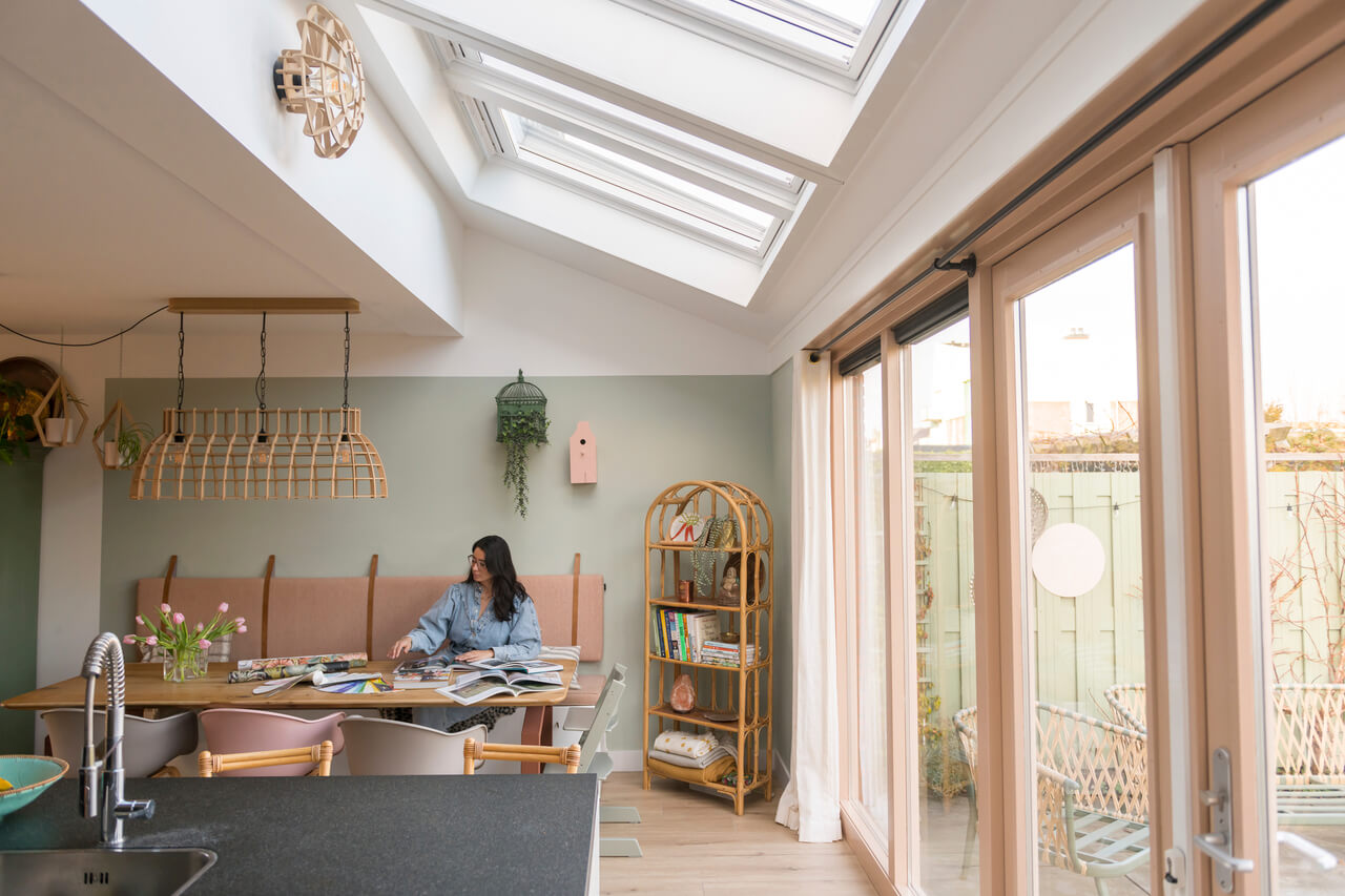 Woman sitting in the bright dining room with lots of light coming from roof windows.