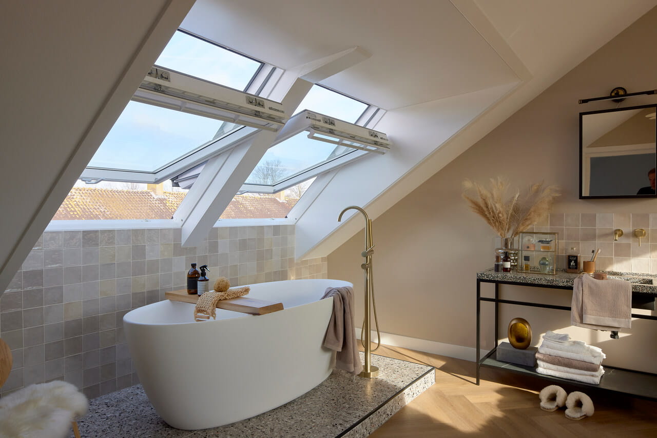 Cozy bathroom are with bath tub and two open roof windows.