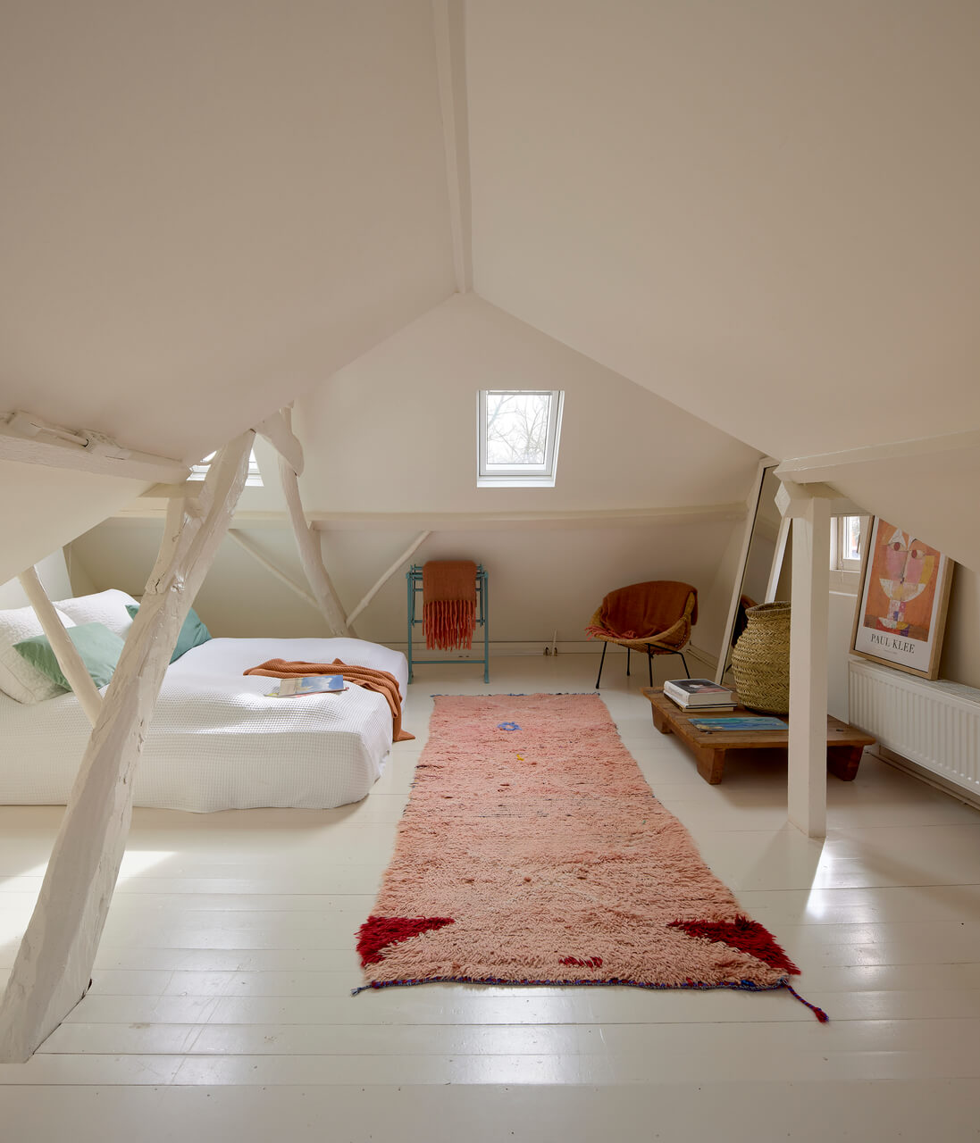 Bright attic space with a bed and roof winodows.