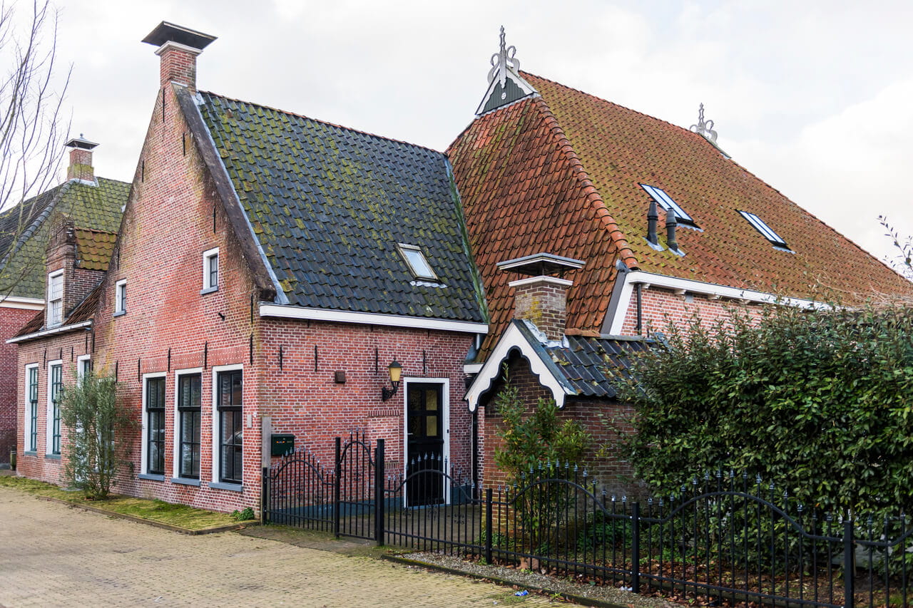 A red brick house with tiled roof and roof windows.