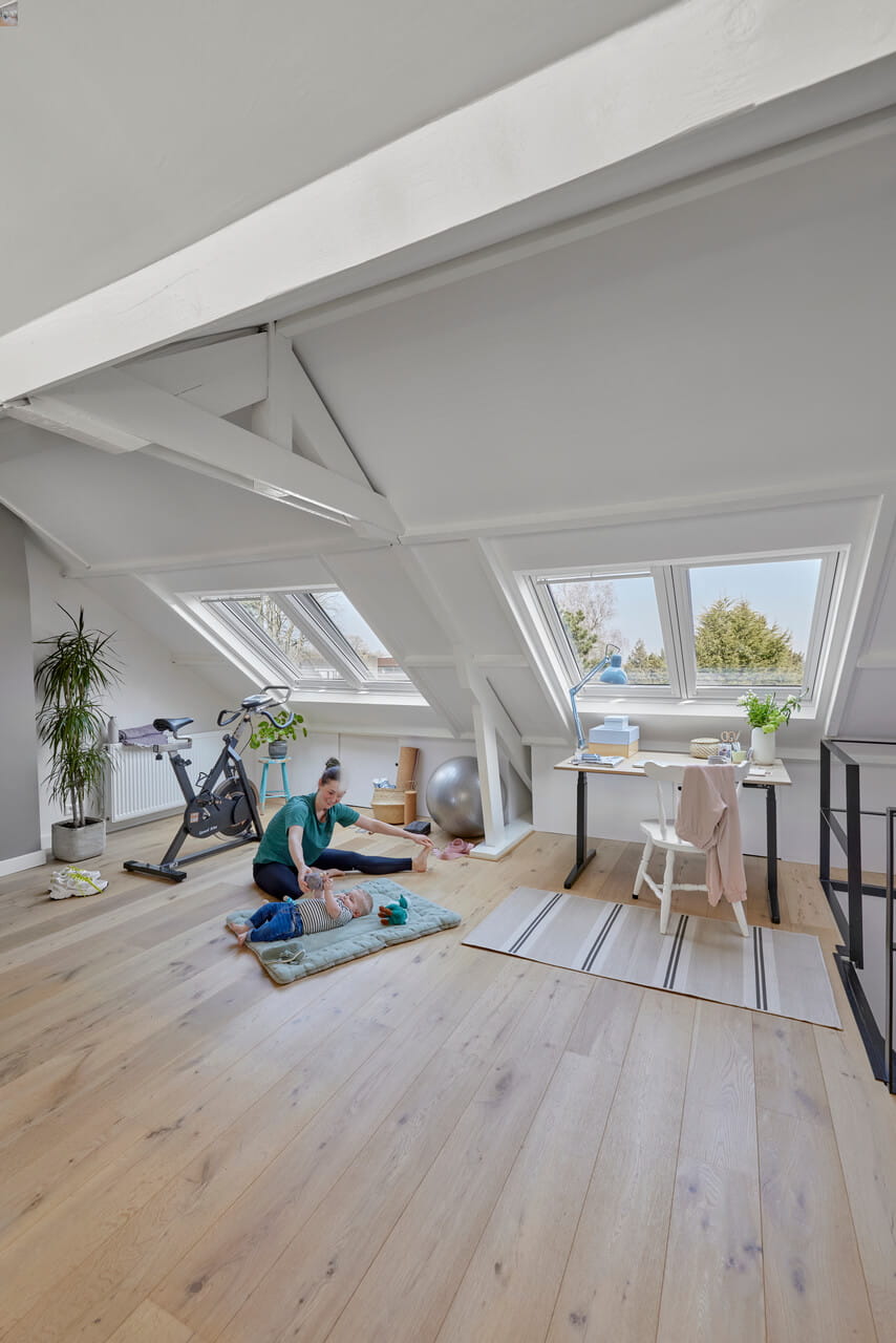 Woman and kid on the ground in the attic wit roof windows.