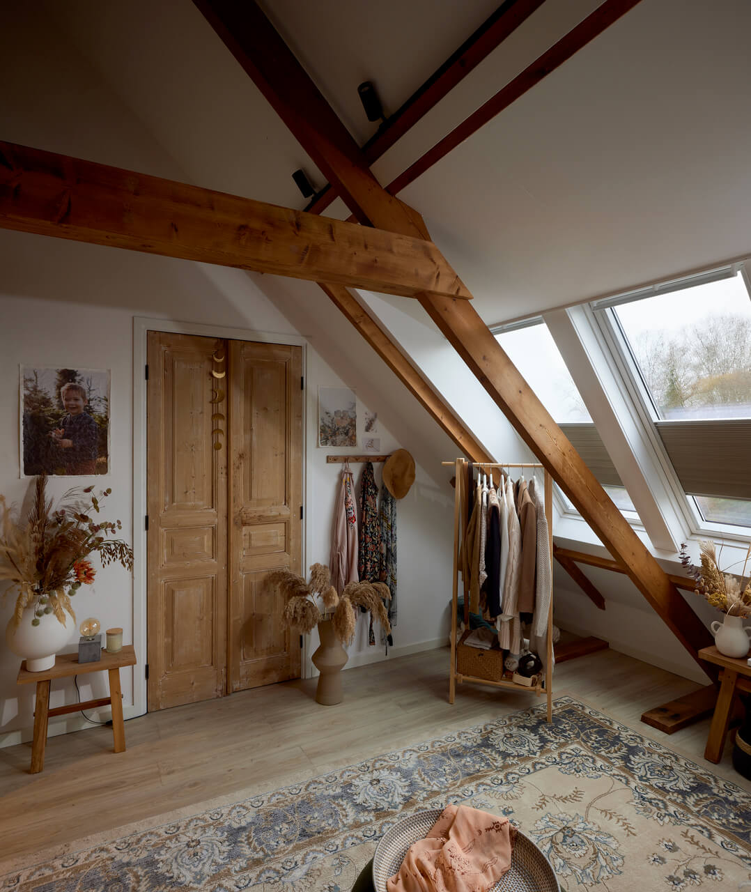 Corner in the attic with hanging clothes and some rustic interior details.